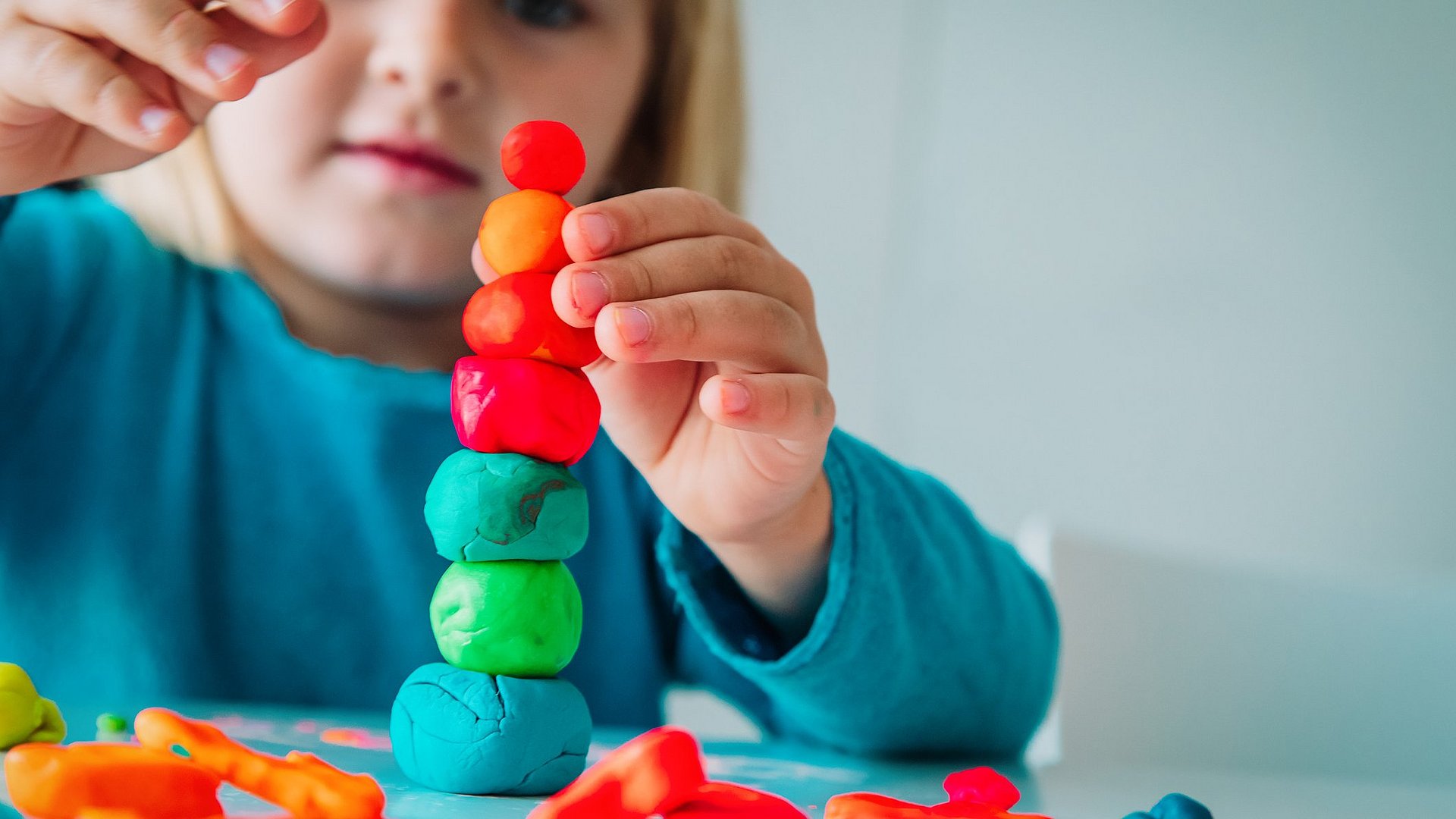 Kleines Mädchen baut aus Knete einen Turm