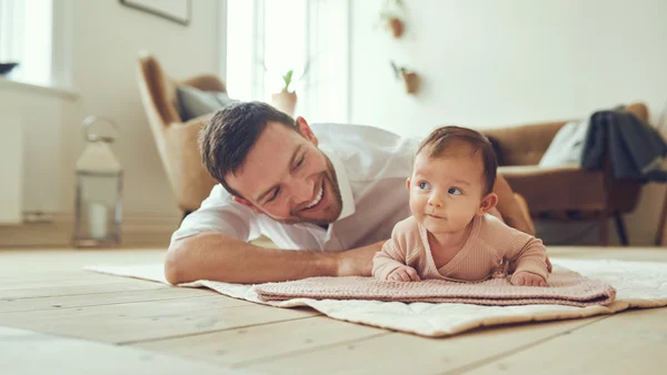 Lächelnder Vater liegt mit seiner Baby Tochter auf dem Boden