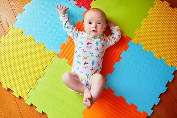Baby liegt auf bunten Matten