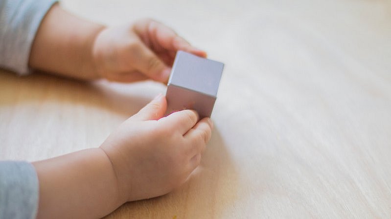 Kleine Hände halten einen viereckigen Würfel