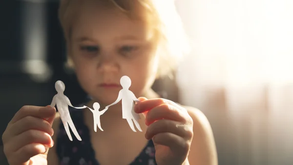 Kind hält Papiermännchen in der Hand