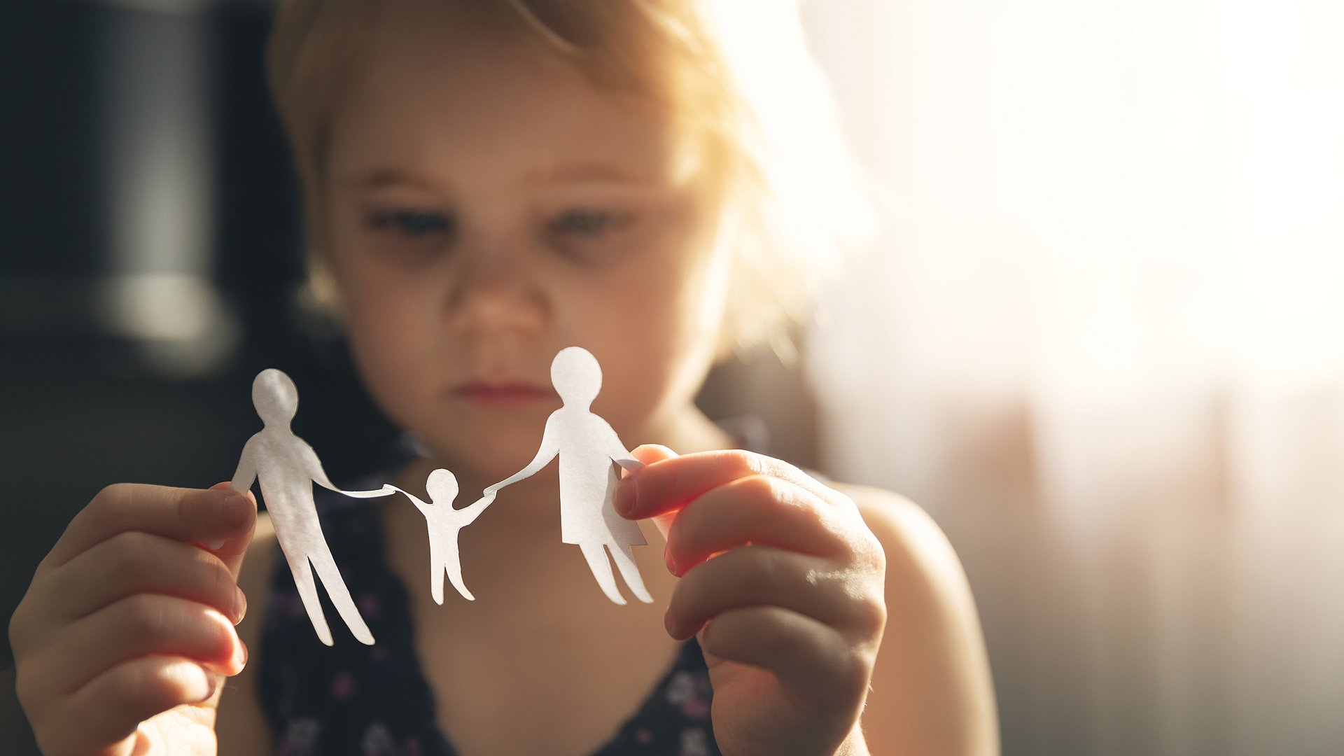 Kind hält Papiermännchen in der Hand