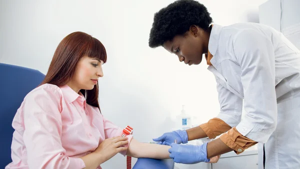 Einer Frau  wird Blut abgenommen