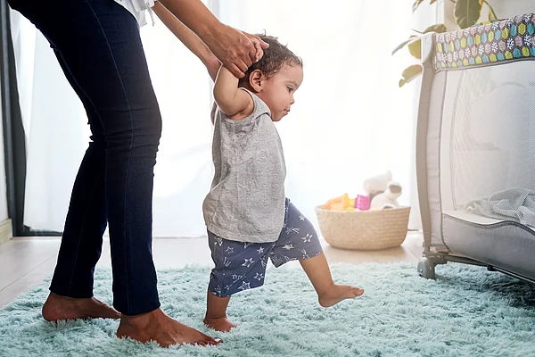 Grosse Hände halten kleine Hände von Baby dass laufen lernt