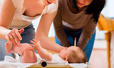 Mutter und Beraterin schauen auf Baby