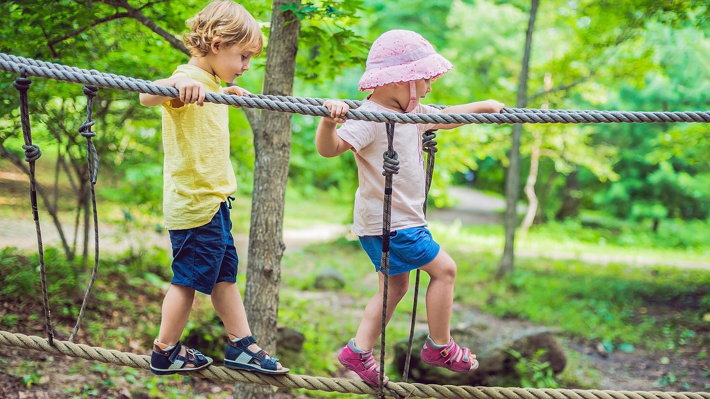 Junge und Mädchen gehen über eine Seilbrücke