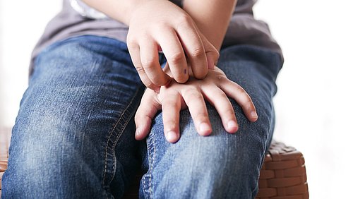 Junge kratzt sich an der Hand