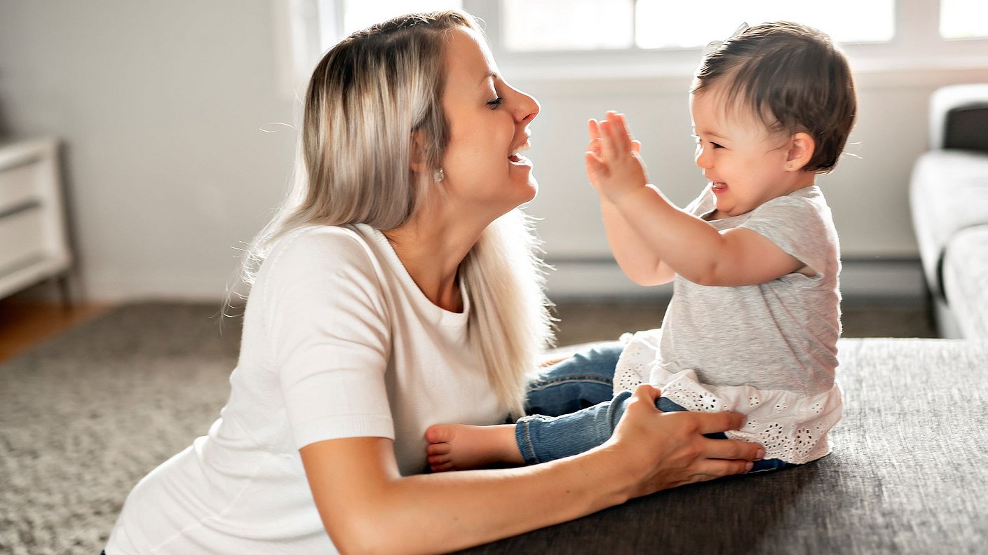Mutter und Baby tochter lachen und spielen zu Hause auf dem Sofa