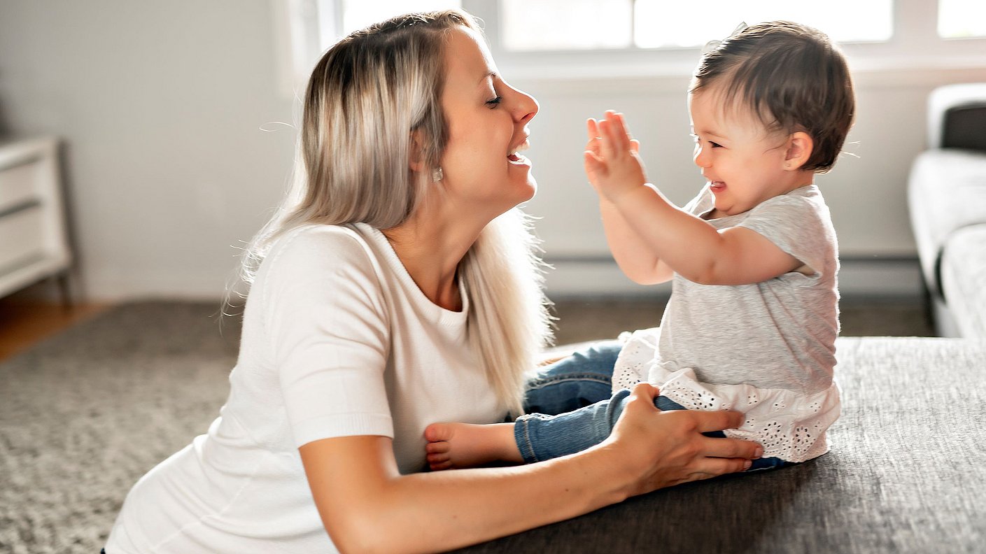 Mutter und Baby tochter lachen und spielen zu Hause auf dem Sofa